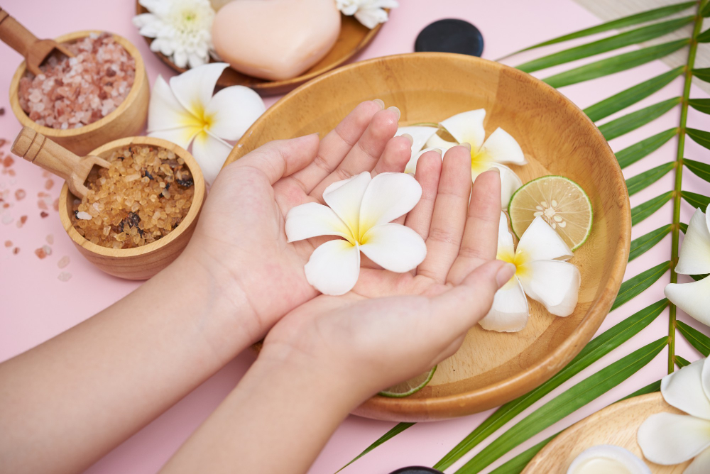 woman-soaking-her-hands-bowl-water-flowers-spa-treatment-product-female-feet-hand-spa-massage-pebble-perfumed-flowers-water-candles-relaxation-flat-lay-top-view